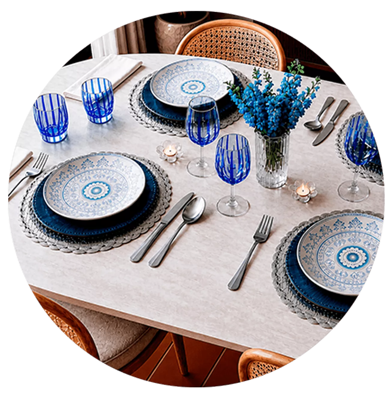 Mesa posta com pratos decorados em azul, taças de cristal e guardanapos